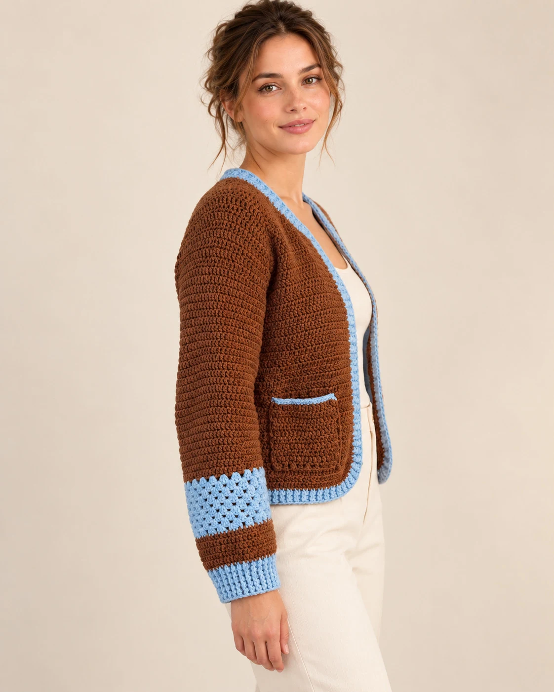 Side view of the Chestnut & Sky Crochet Cardigan showing the patch pocket and sky-blue sleeve band