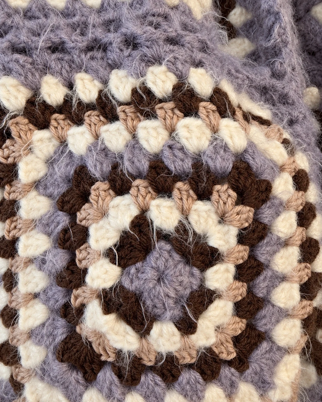 Close-up of lavender, cocoa, beige and cream stitches in a granny square on the cotton cardigan